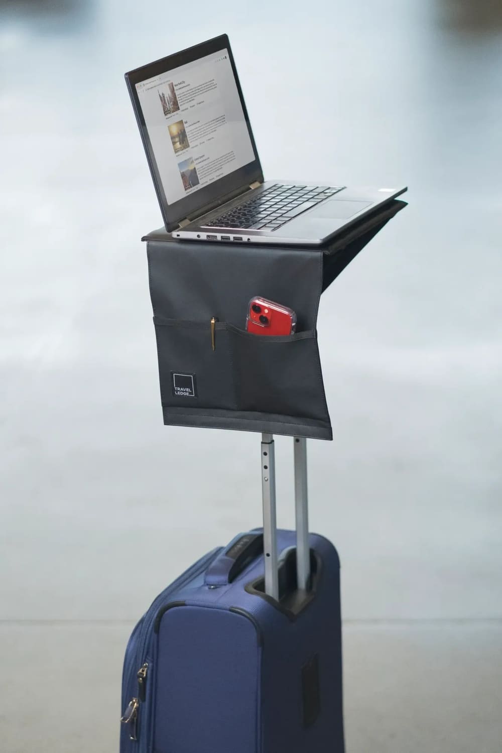 Travel Ledge attached to a blue rolling suitcase with a laptop and travel essentials