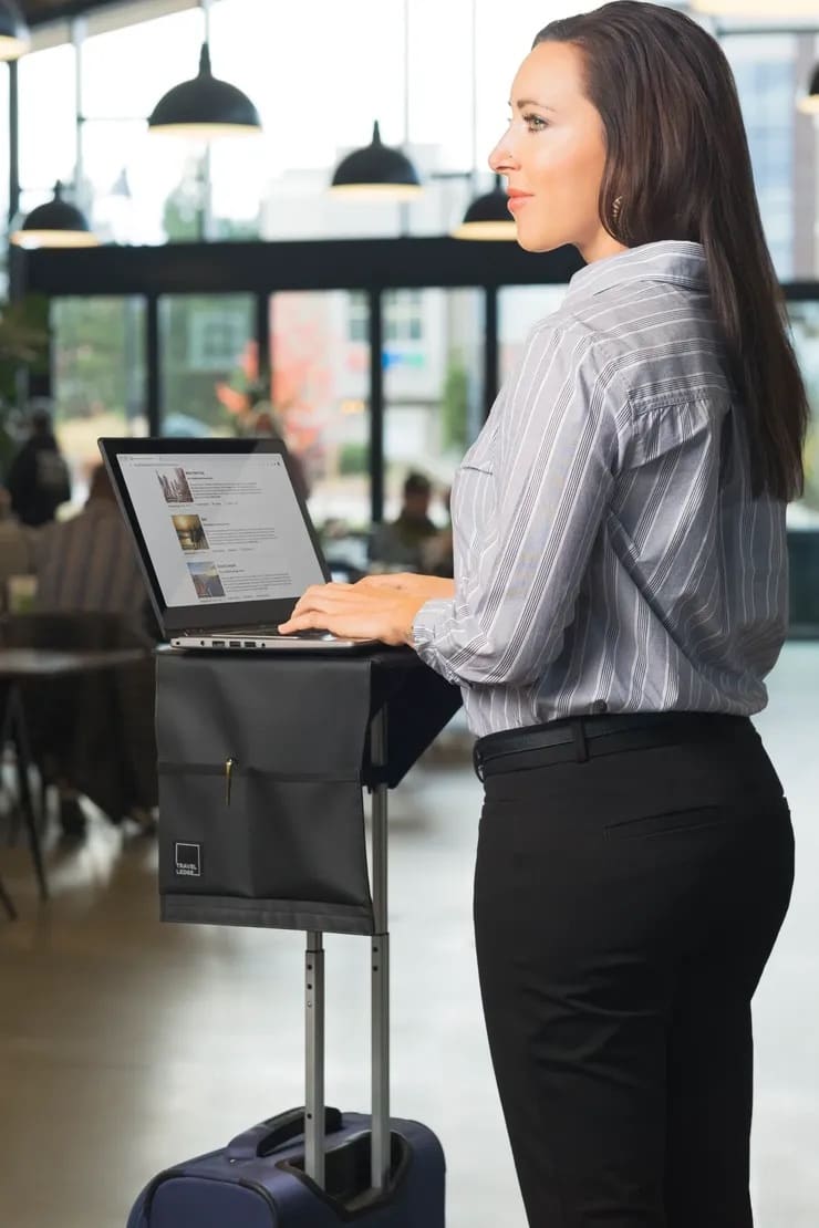 Traveler using a laptop on Travel Ledge attached to rolling luggage